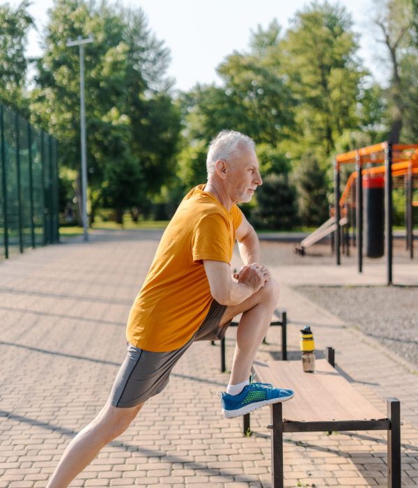 Man étirant les jambes à l'aide d'un banc après une séance d'entraînement en plein air